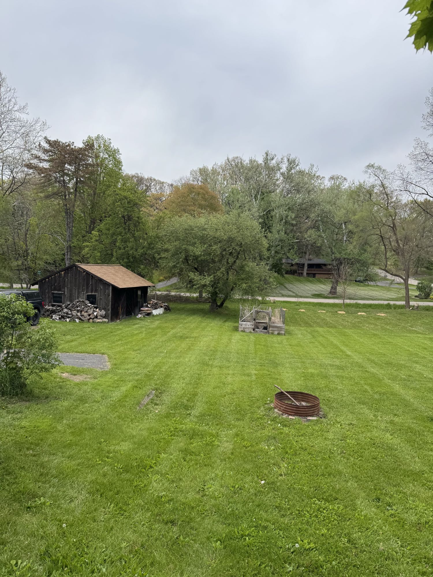 Before: sloped lawn with an old metal fire ring and outbuilding in Ypsilanti, MI